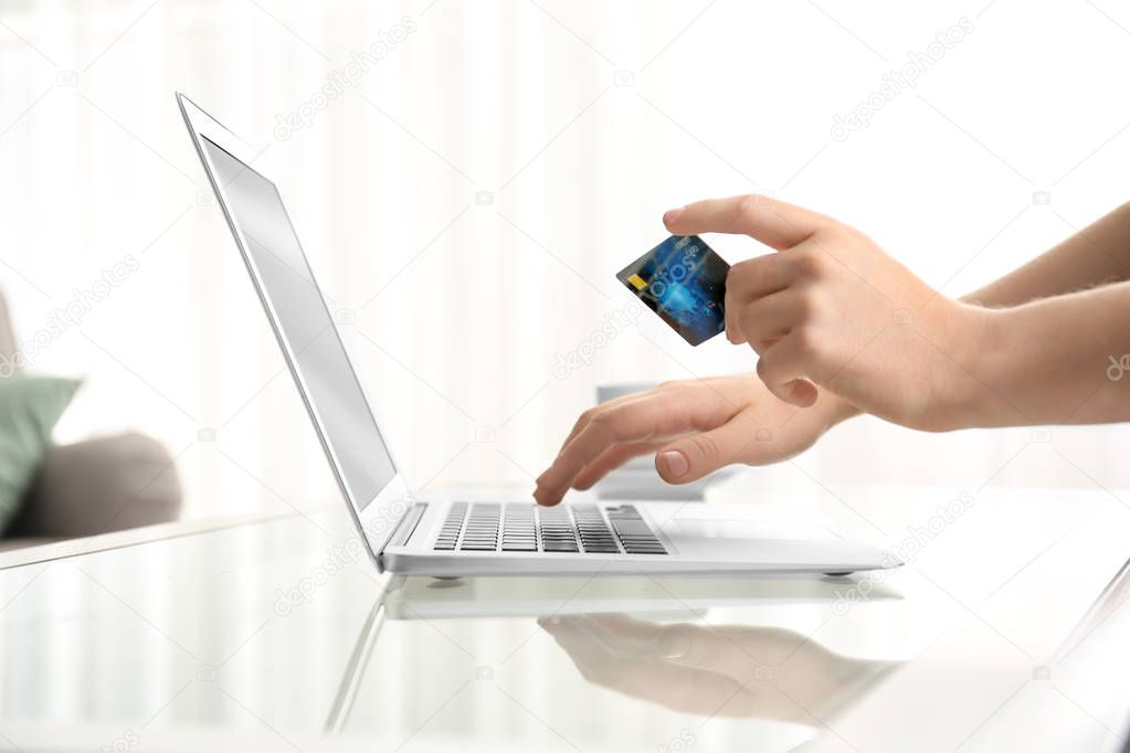 Woman holding credit card while using laptop at home. Internet shopping concept