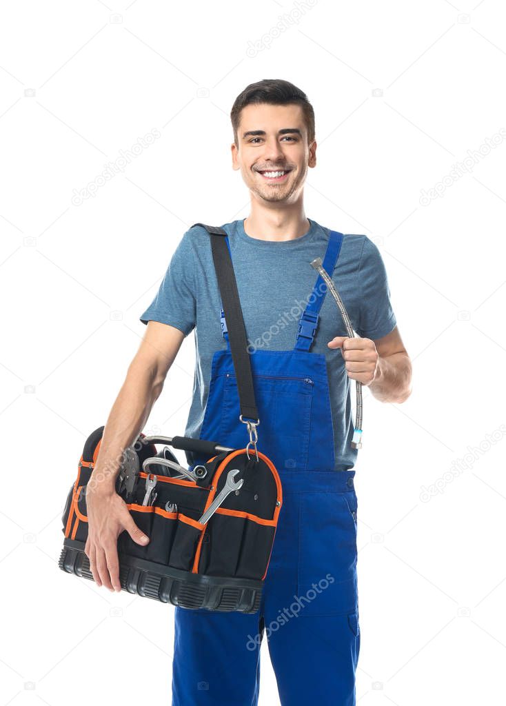 Young plumber in uniform with tool bag and flexible tube on white background