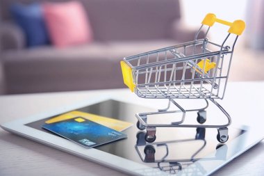 Tablet bilgisayar, alışveriş arabası ve kredi kartları masaya küçük. Internet alışveriş kavramı