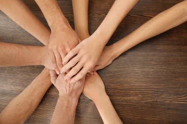 Bir grup insan elleri birlikte ahşap masa üzerinde birlik sembolü olarak koyarak.