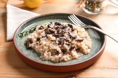 Lezzetli risotto ve çatal ve peçete ahşap masa üzerinde mantar levha