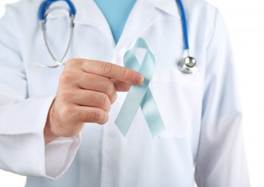 Doktor holding mavi kurdele beyaz arka plan üzerinde. Kanser farkındalık kavramı