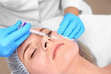 Beautician making injection in woman's face, closeup. Biorevitalization procedure clipart