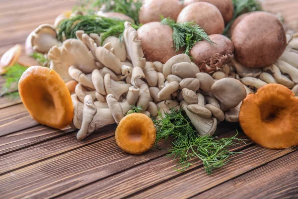 Variety of raw mushrooms on wooden table — Stock Photo, Image