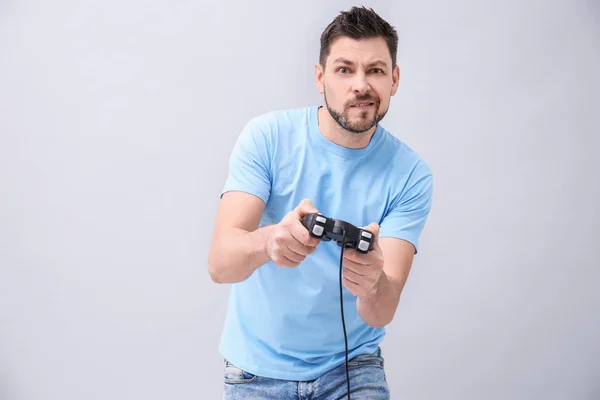 Emotionaler Mann mit Videospielcontroller auf grauem Hintergrund — Stockfoto