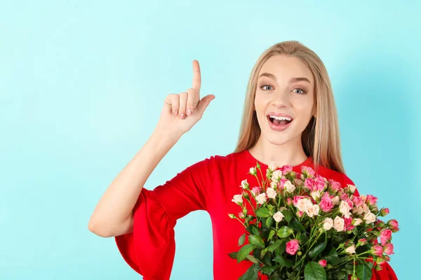 色の背景にバラの花束を持つ美しい若い女性 — ストック写真