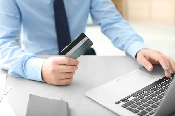 Человек с кредитной картой и ноутбуком за столом — стоковое фото