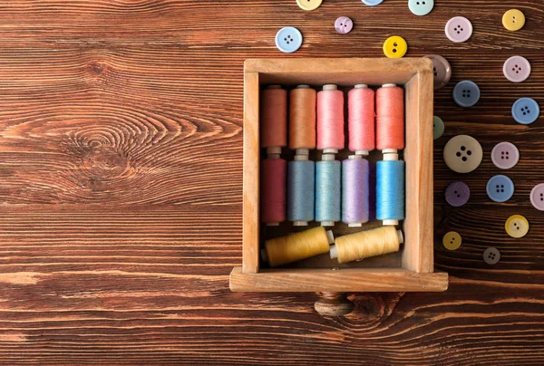 Cajón de madera con hilos de costura de color y botones en la mesa, vista superior — Foto de Stock