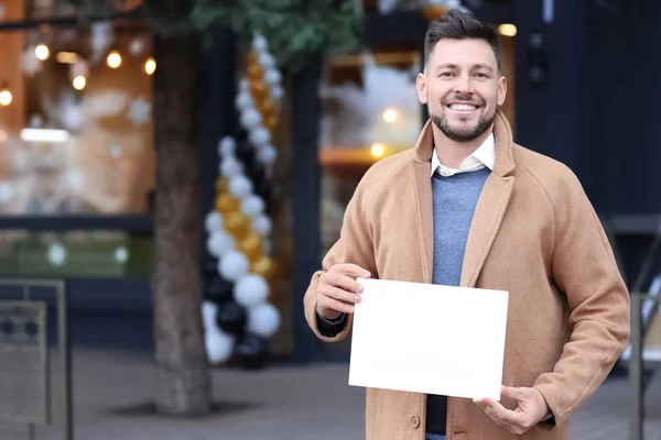 Business ägare håller tomt papper nära sin butik — Stockfoto