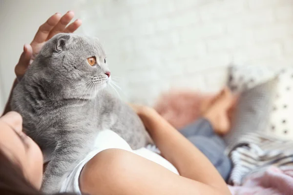 Junge Frau mit süßer Katze auf dem Bett zu Hause — Stockfoto