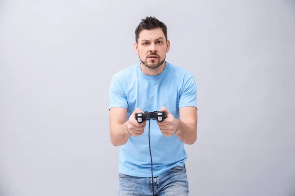 Emotionaler Mann mit Videospielcontroller auf grauem Hintergrund — Stockfoto