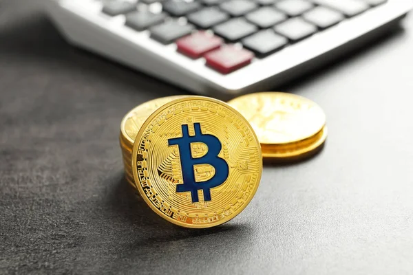 Goldene Bitcoins mit Taschenrechner auf grauem Hintergrund — Stockfoto