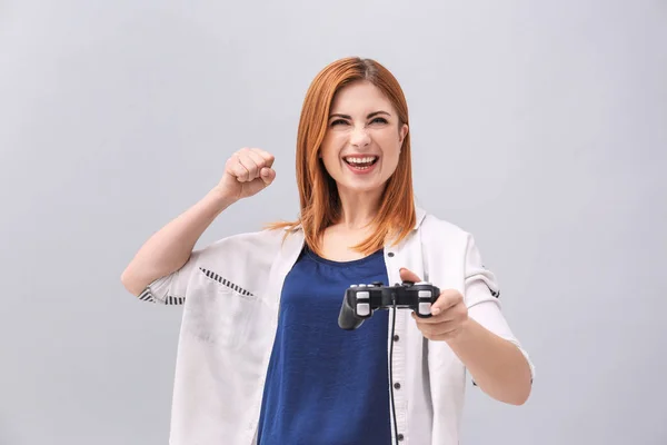 Emotionale Frau mit Videospielcontroller auf grauem Hintergrund — Stockfoto