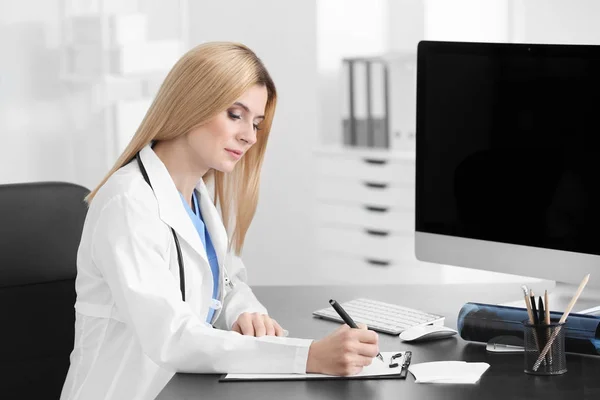 Lekarka, wypełniając formularz zgłoszeniowy w pokoju konsultacji — Zdjęcie stockowe
