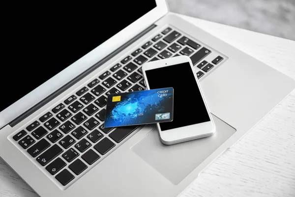 Мобильный телефон и кредитная карта на клавиатуре ноутбука, крупный план. Интернет-магазины — стоковое фото