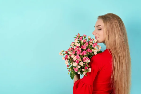Όμορφη νεαρή γυναίκα με μπουκέτο τριαντάφυλλα στο φόντο χρώμα — Φωτογραφία Αρχείου