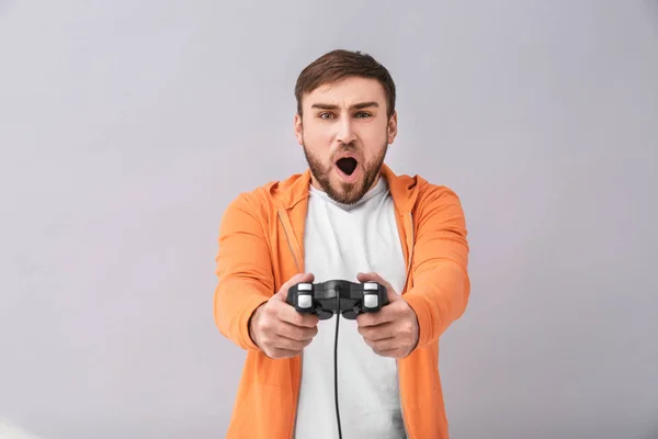 Emotional man with video game controller on grey background — Stock Photo, Image