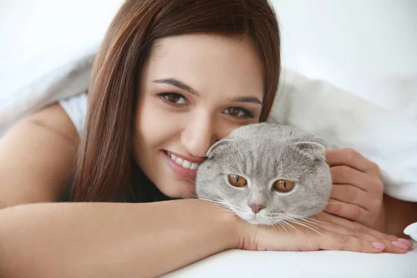 Młoda kobieta z cute domowych kotów w łóżku w domu — Zdjęcie stockowe