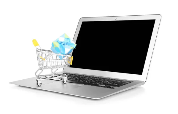 Laptop e piccolo carrello con scatola regalo su sfondo bianco. Internet shopping concept — Foto Stock