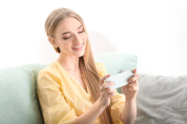 Jovem com aparelho auditivo usando smartphone dentro de casa — Fotografia de Stock