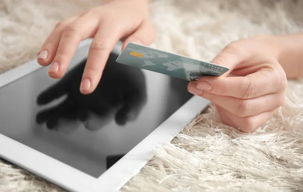 Donna in possesso di carta di credito durante l'utilizzo di tablet a casa, primo piano. Internet shopping concept — Foto Stock