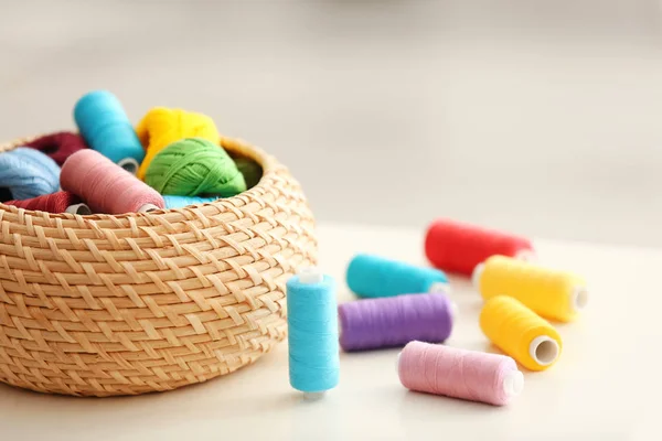 Плетеная коробка с цветными нитками для шитья и крючковыми клювами на столе — стоковое фото