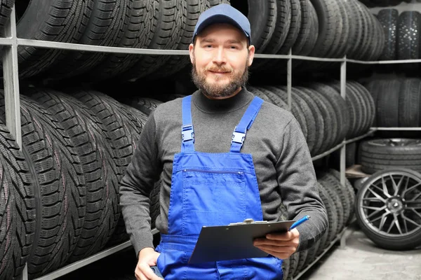 Meccanico maschio con appunti vicino pneumatici auto in negozio di automobili — Foto Stock