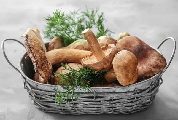Basket with raw mushrooms on grey background — Stock Photo, Image