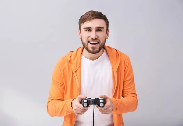 Homem feliz com controlador de videogame em fundo cinza — Fotografia de Stock