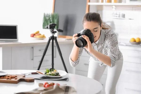 Молодая женщина с профессиональной камерой делает натюрморты фотографии на кухне — стоковое фото