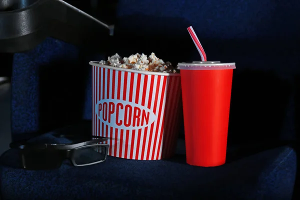 Secchio con gustosi popcorn e cola sulla sedia nel cinema — Foto Stock