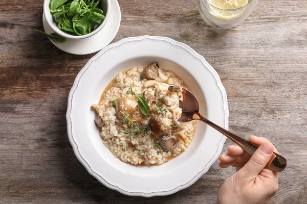 stock image Top view of woman eating delicious risotto with mushrooms at wooden table