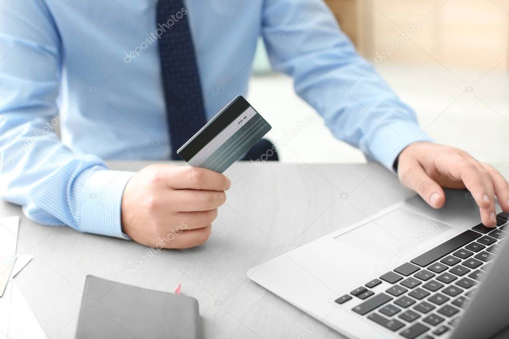 Man with credit card and laptop at table