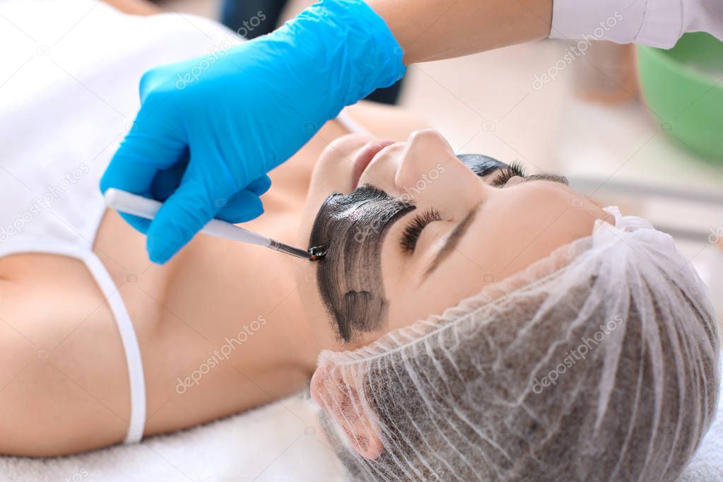 Cosmetologist applying carbon nanogel on woman's face, closeup. Peeling procedure