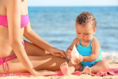 Genç Afrikalı-Amerikalı anne ve kızı ile güneş kremi Beach Resort