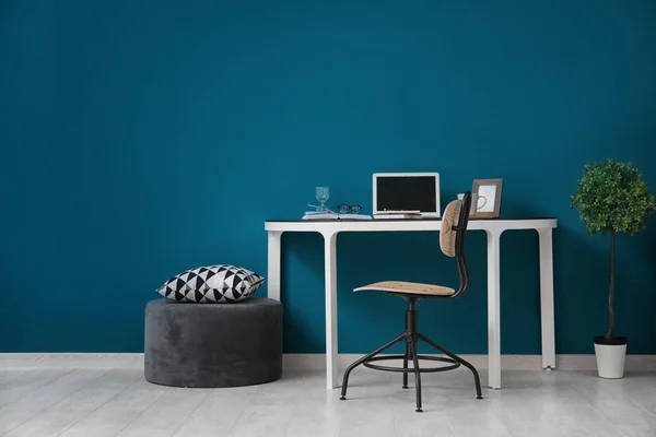 Komfortabler Heimarbeitsplatz mit Laptop auf Schreibtisch gegen farbige Wand — Stockfoto