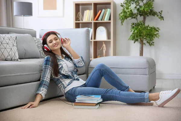 Donna che ascolta audiolibro attraverso le cuffie a casa — Foto Stock
