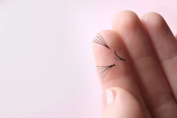 Woman holding false eyelashes on light background, closeup — Stock Photo, Image