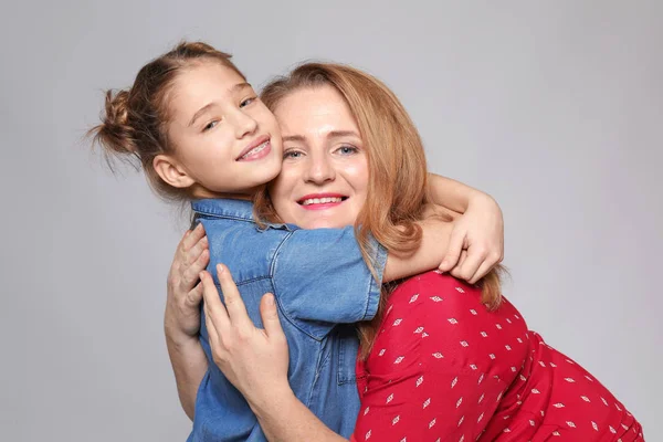 Feliz mãe e filha abraçando no fundo cinza — Fotografia de Stock