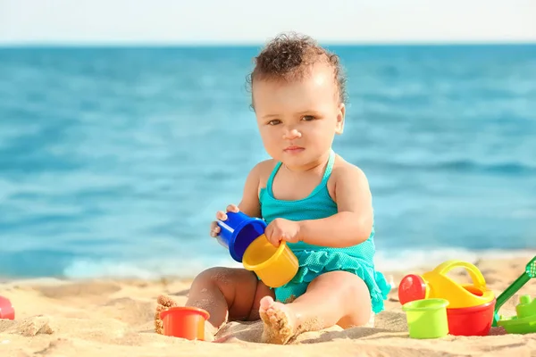 Kleines Mädchen spielt mit Sandspielzeug am Strand — Stockfoto