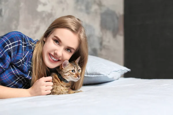 Schöne junge Frau mit süßer Katze auf dem Bett zu Hause — Stockfoto