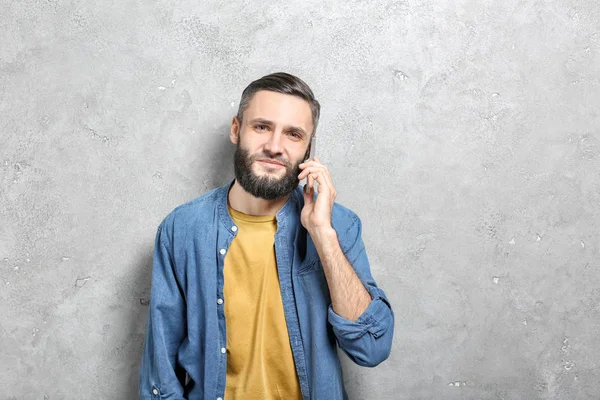Bonito homem falando no celular contra fundo cinza — Fotografia de Stock