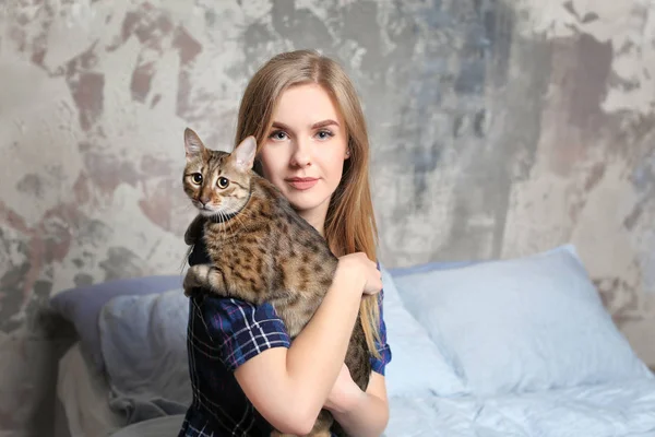 Schöne junge Frau mit süßer Katze sitzt zu Hause auf dem Bett — Stockfoto