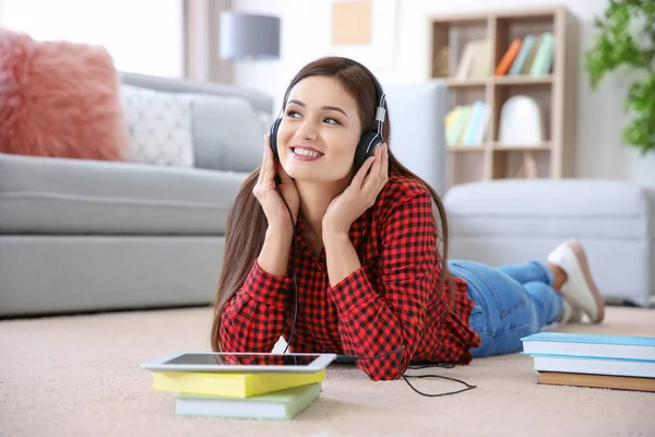 Donna che ascolta audiolibro attraverso le cuffie a casa — Foto Stock