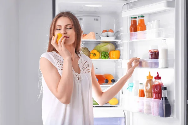 Young woman with fresh lemon standing near refrigerator — Stock Photo, Image