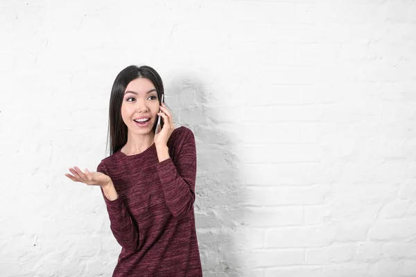 Felice giovane donna che parla sul cellulare vicino al muro bianco — Foto Stock