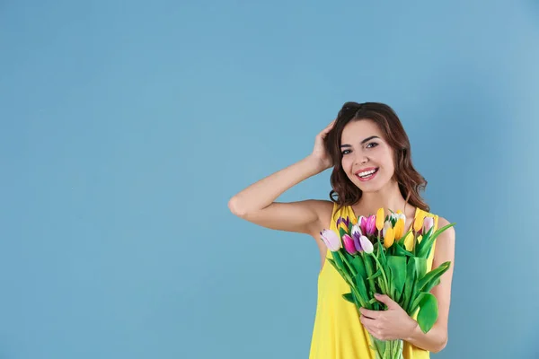 Gyönyörű nő gazdaság tulipán csokor, színes háttérrel — Stock Fotó