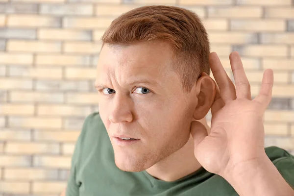 Νεαρός με πρόβλημα ακοής στο τούβλο τοίχο πλαίσιο — Φωτογραφία Αρχείου