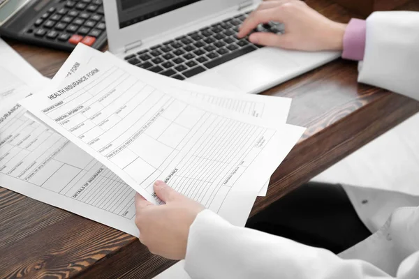 Doctora que trabaja con documentos y laptop en la oficina. Concepto de seguro médico —  Fotos de Stock