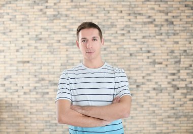 Tuğla duvar arka plan üzerinde rahat kıyafetler içinde genç adam portresi